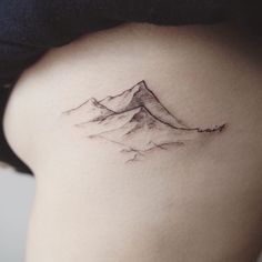 a woman's back with a mountain tattoo on her left side ribcage