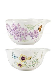 two white bowls with purple flowers and butterflies on the bottom, one is filled with water