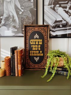 a shelf with books, plants and pictures on it