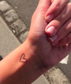 a woman's arm with a small heart tattoo on her left wrist and the word love written in it