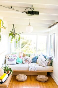 a living room filled with lots of furniture and pillows on top of a hard wood floor