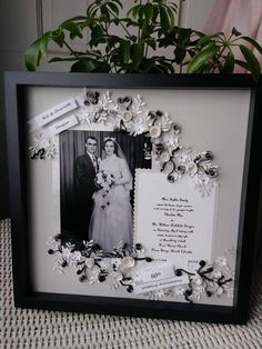 a black and white photo frame with flowers on the bottom, an image of a bride and groom