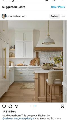 a kitchen with white cabinets and wooden floors, an island countertop and stools