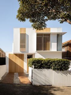 a white house with wooden slats on the front and side walls, next to a tree