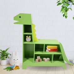 a green dinosaur shaped shelf with books and toys