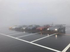 several cars parked in a parking lot on a foggy day