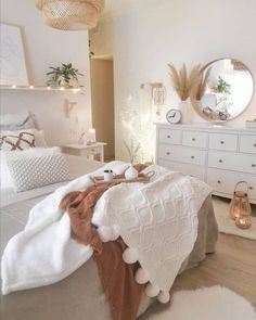 a bedroom with white furniture and lights on the wall, along with a bed covered in blankets