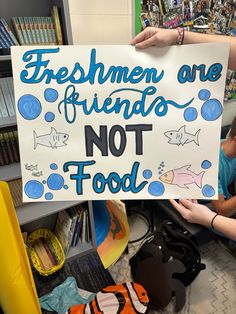 a young boy holding up a sign that says, freshmen are friends not food