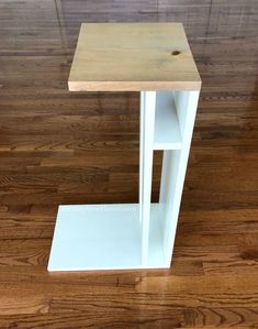 a small white shelf on top of a hard wood floored floor with no one around it