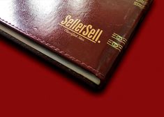 a red leather wallet sitting on top of a red table next to a cell phone