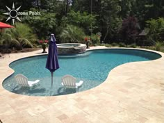 an empty swimming pool with chairs and umbrellas in the foreground, surrounded by greenery