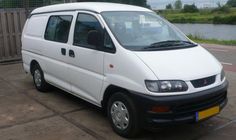 a white van parked on the side of a road next to a body of water