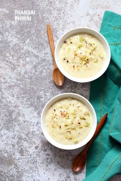 two bowls filled with soup sitting on top of a green napkin next to wooden spoons