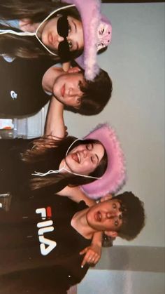 three young women wearing pink ear muffs posing for a photo