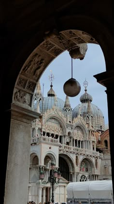 an archway leading to a large building with domes on it's roof and people walking around