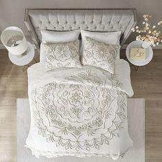 the bed is made with white linens and has an intricate design on it,