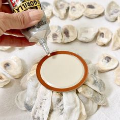 a person is dipping something into a bowl with sauce on it and some oysters in the background