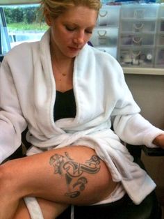 a woman sitting in a chair with a tattoo on her leg