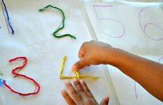 a child's hand is writing numbers with crayons