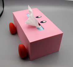 a pink box with an origami horse on the top and two red wheels