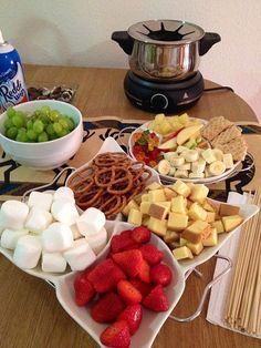 several plates of food on a table with fruit, crackers, and water bottles