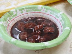 a green bowl filled with meatballs on top of a table next to a banana