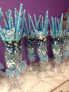 there are many blue and white candies in vases on the counter top with candy