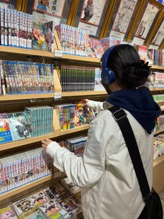 a woman is looking at comics on display in a store with headphones and ear muffs