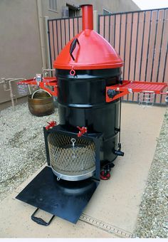 a large black and red stove sitting on top of a cement floor next to a building