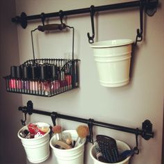 two buckets are hanging on the wall with hair brushes and other items in them