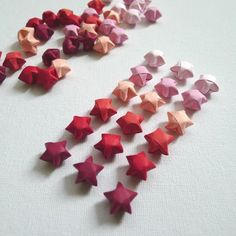 several different colored origami stars on a white table top, with one red and one pink star in the middle