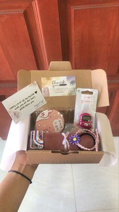 someone is holding a box with various items in it that include bracelets, watch and jewelry