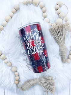 a red, white and blue plaid christmas tumbler next to some tassels