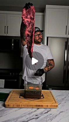 a man holding up a piece of meat on top of a cutting board