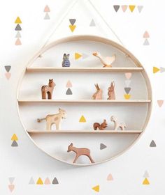 a wooden shelf with various toy animals on it and triangles in the wall behind it