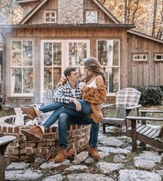 a man and woman sitting on top of a brick fire pit