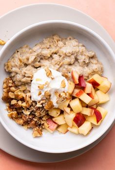 a white bowl filled with oatmeal and fruit on top of a table