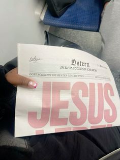 a person holding up a paper with the word jesus printed on it