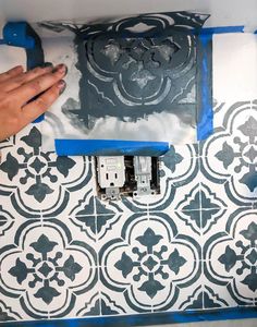 a person is painting a wall with black and white tiles