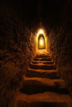 a dark tunnel with stairs leading up to the light