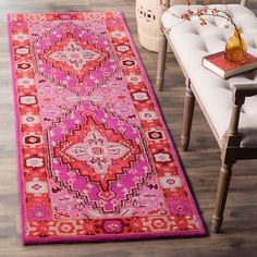 a bright pink rug with an ornate design on the floor next to a white chair