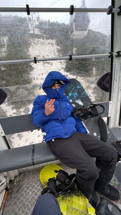 a man sitting on top of a snow covered ski lift holding his hands up in the air