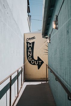 a sign that says hang out on the side of a building next to a stairway