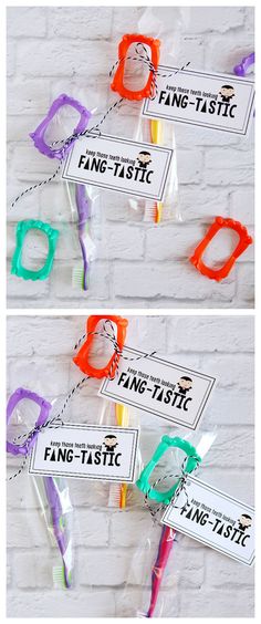 three different colored toothbrushes in plastic bags on a white brick wall with tags attached to them