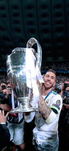 a man holding up a silver trophy in front of a group of people at a sporting event