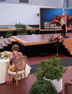 the stage is set up for an event with people sitting at tables and flowers in vases