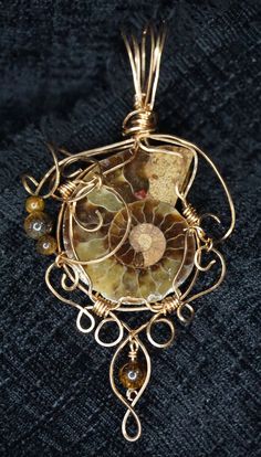 This pendant is a hand made bronze wire wrapped ammonite, accented with tiger eye beads.  This will be shipped with an eighteen inch length of satine cord, so that the length of the necklace can be adjusted.  Alternatively, a bronze chain can be fabricated for an additional charge.  You can see me make items like this live on my Twitch.tv channel at https://www.twitch.tv/growlingmousestudio Bronze Wire-wrapped Round Pendant Jewelry, Bronze Wire Wrapped Round Pendant Jewelry, Nature-inspired Gold Wire Wrapped Jewelry, Unique Brown Spiral Jewelry, Bronze Spiral Wire Wrapped Jewelry, Bronze Wire Wrapped Spiral Jewelry, Spiral Wire Wrapped Brass Jewelry, Spiral Brass Wire Wrapped Jewelry, Brown Spiral Jewelry As A Gift