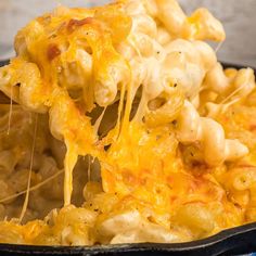 a pan filled with macaroni and cheese being lifted from it