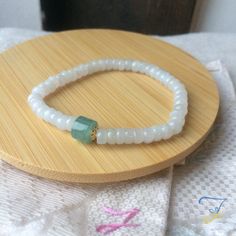 "Dainty Grade A Burmese Icy Jadeite Jade Beaded Bracelet, Grade A Burma icy White Jadeite, Guatemalan Icy Blue Green Jade, 14KGF, 簡約冰膠翡翠手串 This bracelet is made of 14k gold filled pieces, Burma icy white jade, and Guatemalan icy blue green jade. This bracelet is threaded by a white elastic thread, it's ajustable. Those white jade beads have an gélatinous and slightly icy foundation. Some of those beads have visible structure traces (inside) and their forms aren't all in rondelle. The blue jade bead is of Guatemalan icy jade. This jade has an icy transluscent foundation. This jade has a very intense stone structure, it's a very good quality jade. The golden pieces are of 14k gold filled. --------------------------------------------------------------- Les photos sont prises avec le produit r Handmade White Jade Bracelets, White Jade Crystal Bracelet, White Adjustable Jade Bracelets, Adjustable White Jade Beaded Bracelets, White Stretch Bracelet With Faceted Beads For Healing, Handmade White Jade Beaded Bracelets, Hand-strung White Jade Beaded Bracelets, White Beaded Jade Jewelry, White Jade Beaded Jewelry