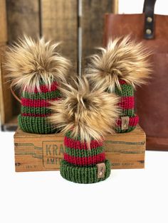 two knitted hats sitting on top of a wooden box next to a brown bag